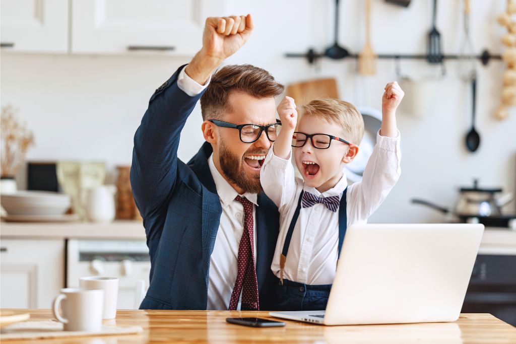 Father and son celebrating success together at a laptop, symbolising focus, connection and support through therapy for ADHD and learning challenges