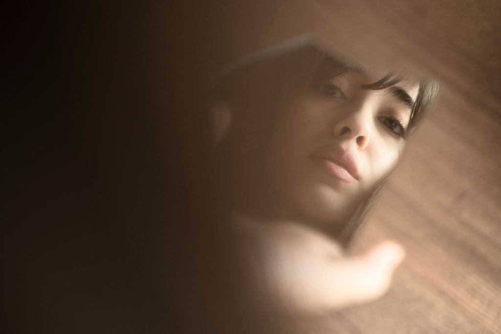Woman gazing at her reflection, symbolising body image concerns and emotional distance
