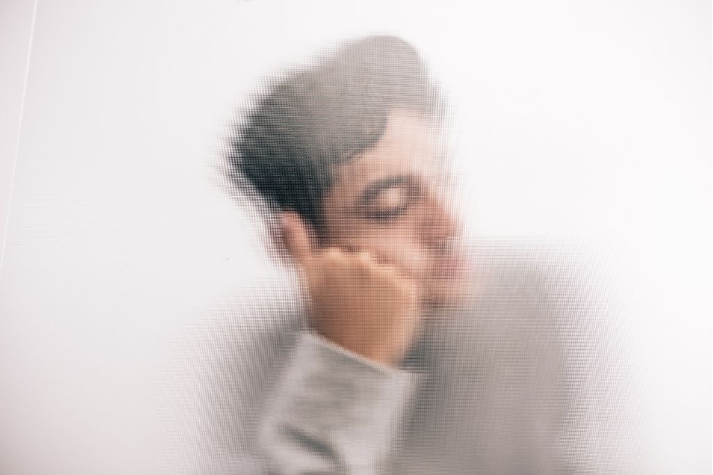 Man behind frosted glass appearing withdrawn