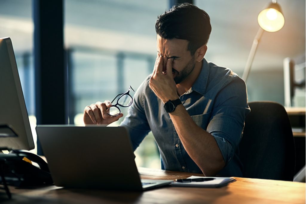 Man sitting at a desk looking stressed, taking a moment to gather himself