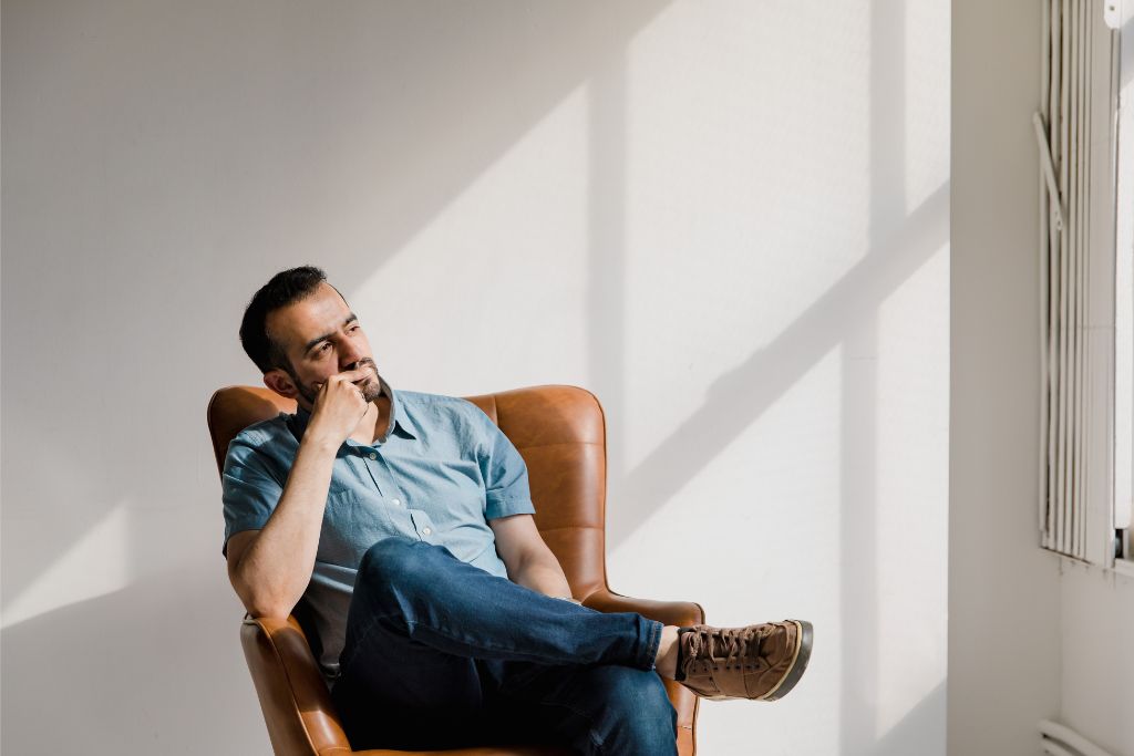 Man seated in quiet room, reflecting during an individual therapy session