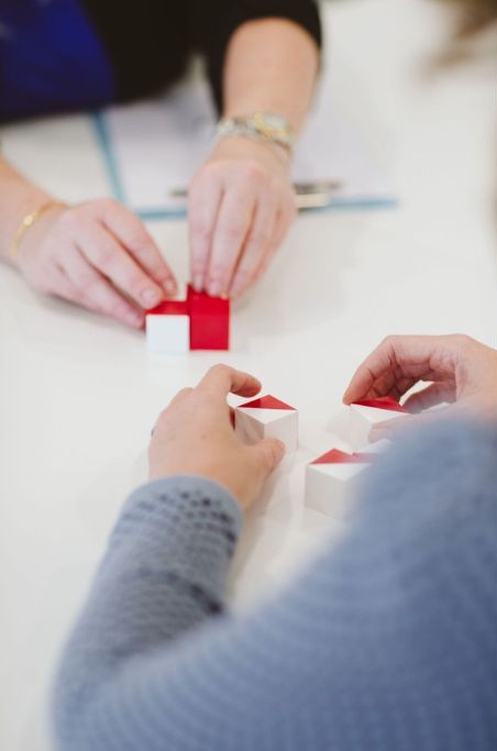 A person completing a cognitive task with red and white blocks during a psychological assessment.