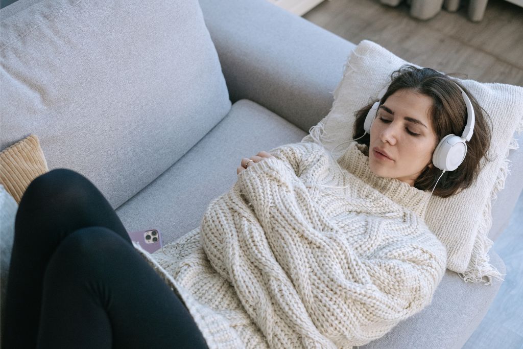 Person relaxing on a sofa with headphones on, showing a calming sensory-friendly environment
