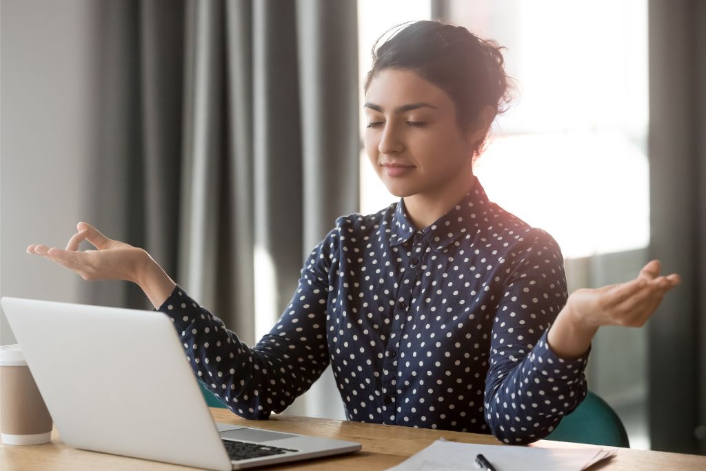 Professional woman practising mindfulness at her desk as part of a corporate wellness programme