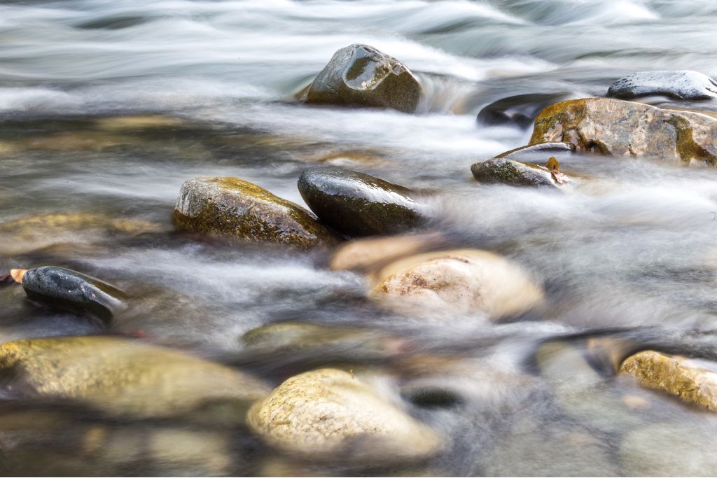 Smooth stones in flowing water, symbolising balance and adaptability