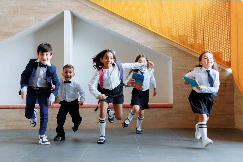Happy children running together outside a modern school building