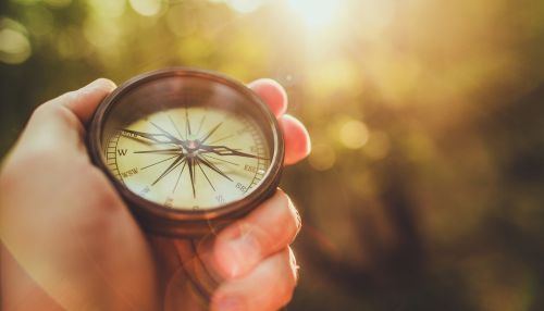 Hand holding a compass toward sunlight, symbolising guidance and ethical direction