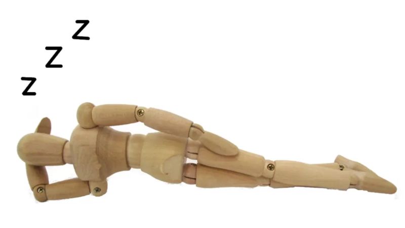 Wooden mannequin sleeping under a blanket symbolising practical sleep tips